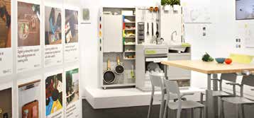 Concept Kitchen 2025, a white kitchen installation beside a dining table and a wall of research panels.